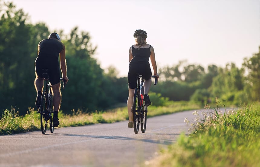 Two person on bicycles riding on a bike path.